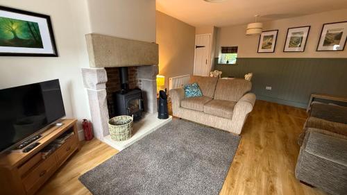 a living room with a couch and a fireplace at Wisteria Cottage in Eyam