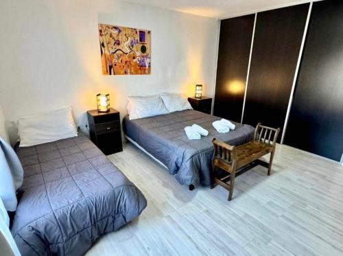 a hotel room with two beds and a chair at Alba Austral, casa amplia y luminosa in El Calafate