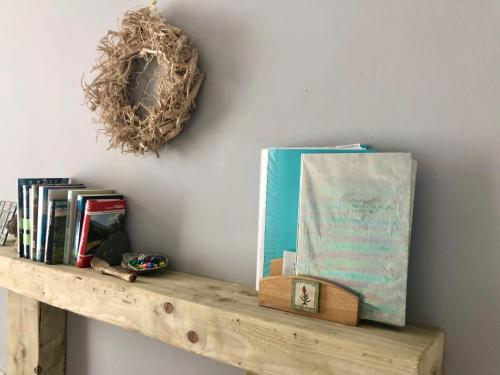 a shelf with books and a wreath on a wall at Simple Welsh Terrace with Valley Views in Morriston