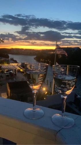 two wine glasses sitting on a table with the sunset at Lagoon Front, Loveladies, Dock, Decks, Beach Badges, Bikes, Ping Pong Table, Foosball, Wifi,gorgeous Reverse-Living Loveladies Contemporary On A, in Loveladies