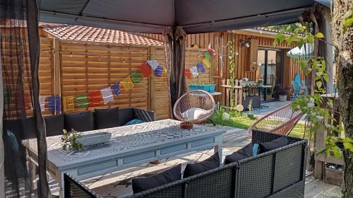 un patio avec une table et des chaises sous un parasol dans l'établissement Entre Bassin et lacs, à Gujan-Mestras