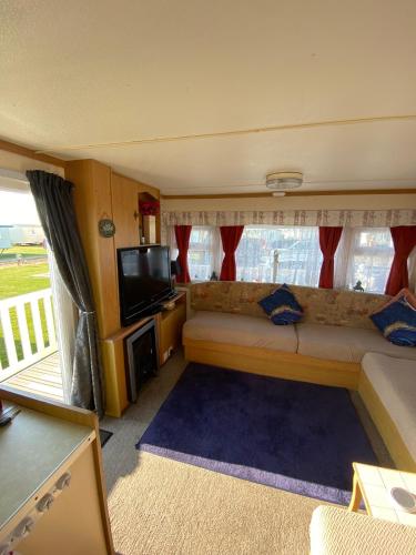 a living room with a couch and a flat screen tv at i13 the chase caravan park in Ingoldmells