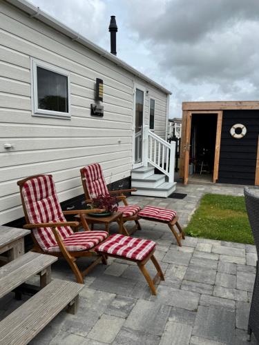 two chairs and a table on a patio next to a house at Prachtig chalet de ZEE STER in Westerland