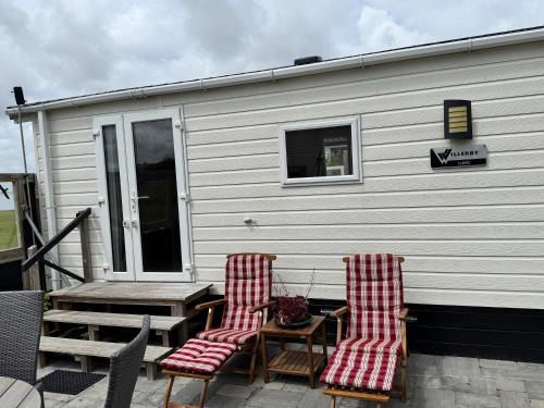 two chairs and a table on the back of a house at Prachtig chalet de ZEE STER in Westerland