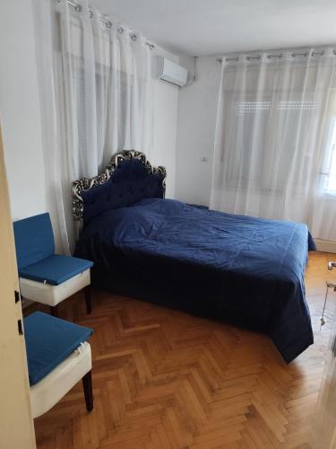 a bedroom with a blue bed and a chair at Sweet Dream Rooms in Podgorica