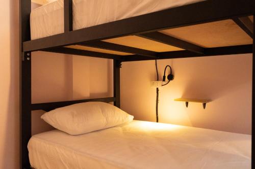 ein Schlafzimmer mit einem Etagenbett und einem weißen Kissen in der Unterkunft TIDE & TRIBE HOSTEL Phangan in Thongsala