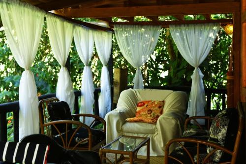a chair on a porch with white curtains at Casa de Piedra in Mindo