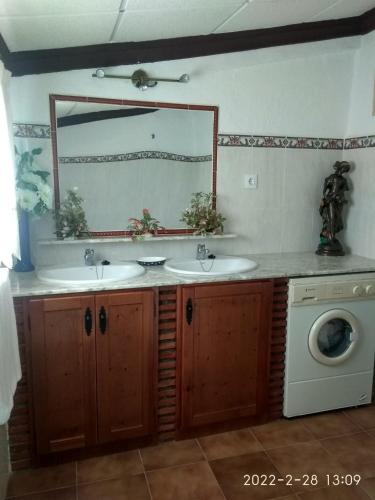 a bathroom with a sink and a mirror and a washing machine at CASAS CUEVAS ELVIRA in Hinojares