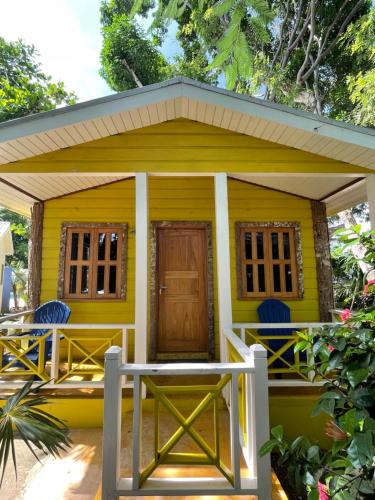 a small yellow house with a porch and a door at Bak A Yaad in Negril