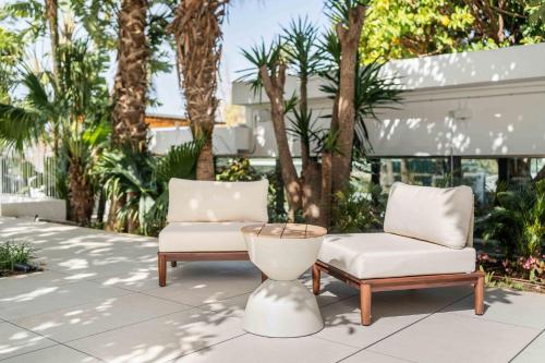 two chairs and a table on a patio with palm trees at Kimpton Los Monteros Marbella by IHG in Marbella