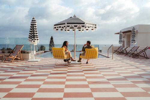 two people sitting in chairs under an umbrella on a roof at Kimpton Los Monteros Marbella by IHG in Marbella