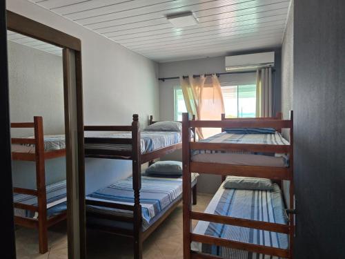 una habitación con tres literas y un espejo en Casa na Enseada da Pinheira, en Palhoça