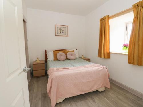 a bedroom with a bed with pink sheets and a window at Bathach Beag in Oban