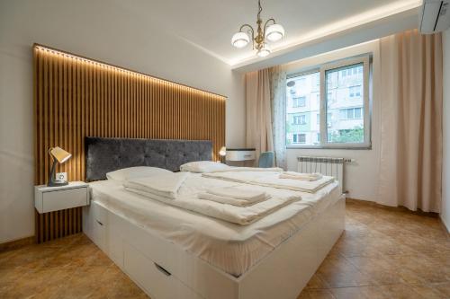 a bedroom with a large white bed with a large window at Marble place in Sofia
