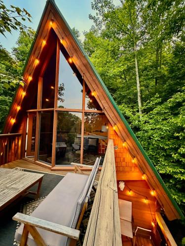 a cabin with a porch with a bench and lights at Charming A-Frame Cabin w Hot Tub & Mountain Views in Gatlinburg