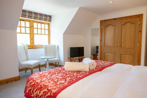 a bedroom with a bed and two chairs and a television at Old Distillery Lodge in Kingussie