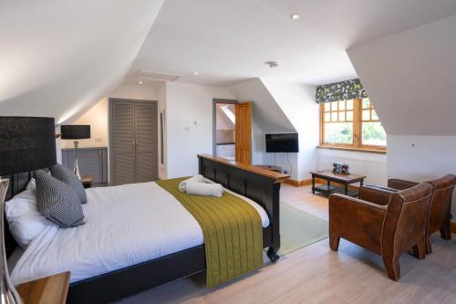 a bedroom with a king sized bed and a chair at Old Distillery Lodge in Kingussie