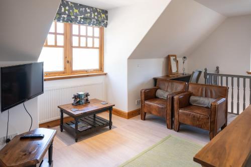 a living room with a chair and a television at Old Distillery Lodge in Kingussie