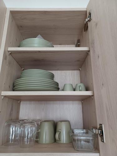 un placard rempli de plats verts et de bols en verre dans l'établissement T2 neuf 2024, terrasse, parking, RER B et VAL à 2 pas, à Antony