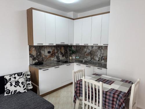 a kitchen with white cabinets and a table and chairs at Orkidea Apartments in Golem