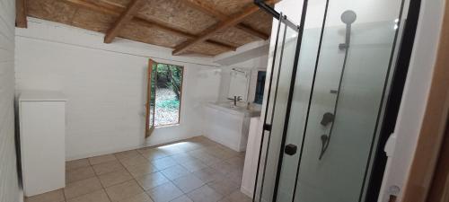 La salle de bains est pourvue d'une douche, d'un lavabo et d'une porte. dans l'établissement Maison de vacances de famille sous les pins, à Gujan-Mestras