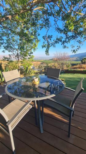 a glass table and two chairs on a wooden deck at la noach in Metulla