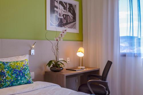 a hotel room with a desk with a bed and a chair at Blue Tree Towers Valinhos in Valinhos