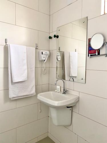 a bathroom with a sink and a mirror and towels at Hotel Dom Rafael Business in Santa Maria