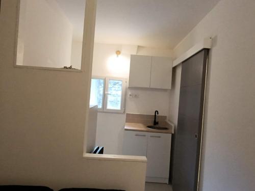 Elle comprend une petite cuisine avec des placards blancs et une fenêtre. dans l'établissement Charmant petit duplex en Provence, à Cabasse