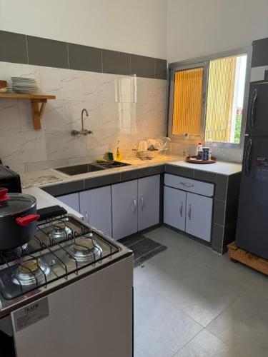 a kitchen with a stove and a sink and a refrigerator at Short-Term 2BR Apartment - 2 min from US Embassy, Cocody Riviéra Golf, Abidjan in Abidjan