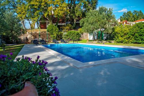 a swimming pool in a yard with purple flowers at Isolated Villa Terna -Big Garden-Pool-Dalmatia in Slime