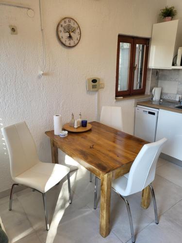 a wooden table with white chairs and a clock on the wall at Olive and Herb Retreat II in Valtura