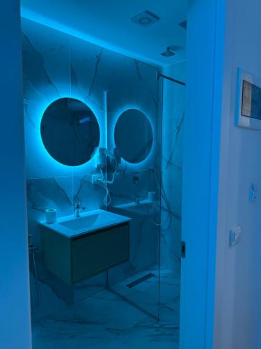 a blue bathroom with a sink and mirror at Suite Rana Hedhun in Shëngjin