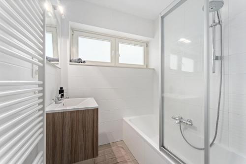 Un baño blanco con lavabo y ducha. en Hotel Van Brugge D2, en De Haan