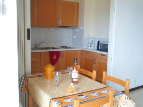 - une cuisine avec une table et une bouteille de vin dans l'établissement Appartement avec balcon, parking, clim et animaux admis proche des Thermes - FR-1-503-18, à Balaruc-les-Bains