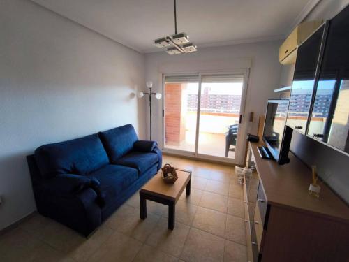 ein Wohnzimmer mit einem blauen Sofa und einem Tisch in der Unterkunft Apartamento con terraza, piscina y vistas en Oropesa del Mar Edificio Torremar in El Borseral