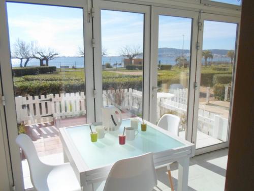 d'une table et de chaises blanches sur un balcon avec fenêtres. dans l'établissement Appartement T2 avec Jardinet Privatif, Proche de l'Étang de Thau et Thermes - FR-1-503-79, à Balaruc-les-Bains