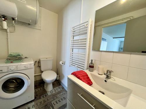 une salle de bain avec une machine à laver et un lavabo dans l'établissement Appartement mezzanine au calme, à La Rochelle