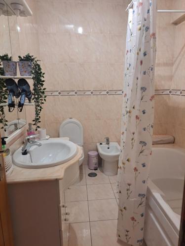 a bathroom with a sink and a toilet and a shower curtain at Casa Barbara in Lagos
