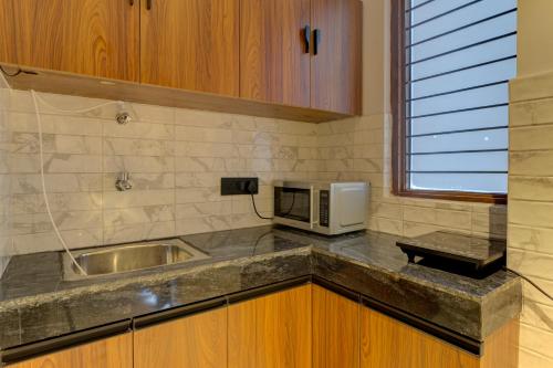 a kitchen with a sink and a microwave at Aura Homes 1 BHK Serviced Apartment Near Golf Course Road Gurgaon in Gurgaon