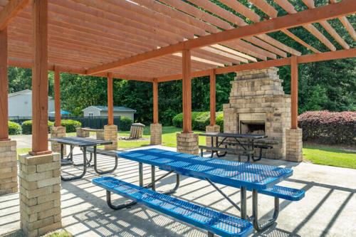 a patio with two picnic tables and a stone fireplace at Spacious 1 Bed 15 Bath Towmhome I Ellenwood in Ellenwood
