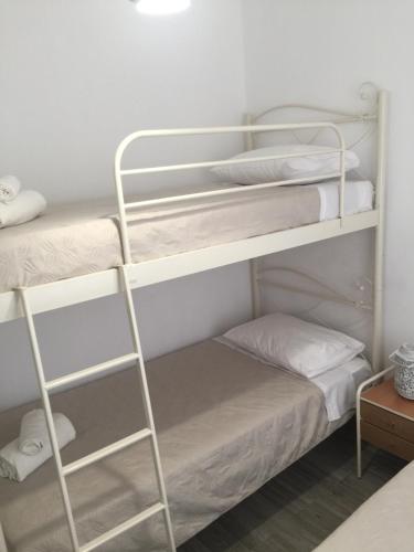 a room with two bunk beds with white sheets at Denise House in Vromolithos