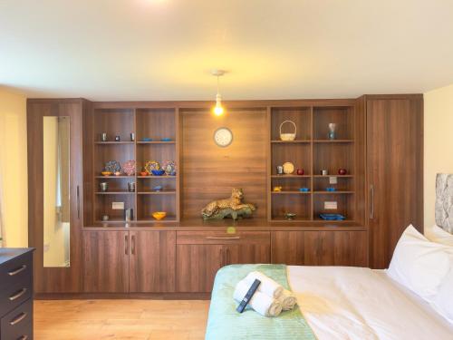 a bedroom with wooden cabinets and a bed in a room at Heathrow Lodge BnB in Harmondsworth