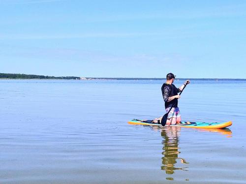 a man standing on a paddle board in the water at Hundi Holiday Home Main House in Hiiumaa