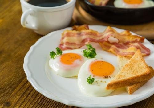 a plate of eggs and bacon and toast on a table at The LaSalle Hotel, Bryan College Station, a Tribute Portfolio Hotel in Bryan