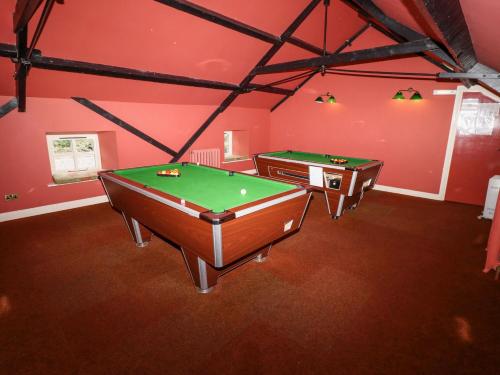 two pool tables in a room with red walls at Hollyhock in Wooler
