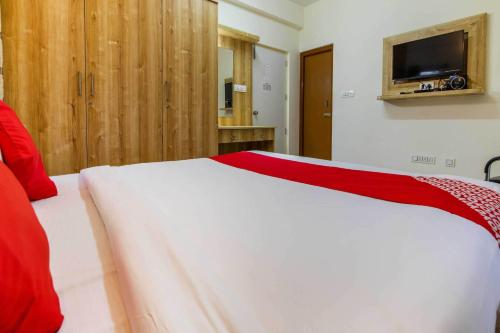 a bedroom with a white bed and a tv on the wall at Hotel O Sagar Comforts in Bengaluru