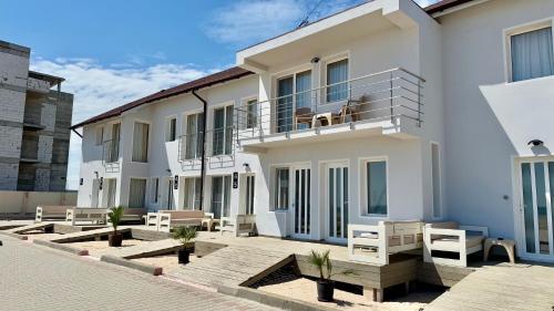 a white building with a balcony and benches at Vila Plaja Azur in Eforie Nord