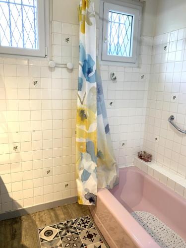 La salle de bains est pourvue d'une baignoire rose avec un rideau de douche. dans l'établissement T3 dans villa 