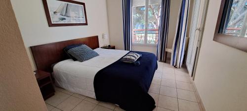 a small bedroom with a bed with a blue blanket at T3 bord de mer in Mandelieu-la-Napoule